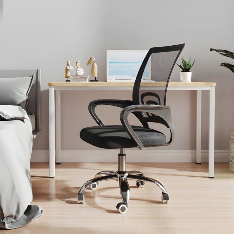 Black mesh clerical office chair with chrome swivel base, lumbar support, and curved armrests in a home office setting.