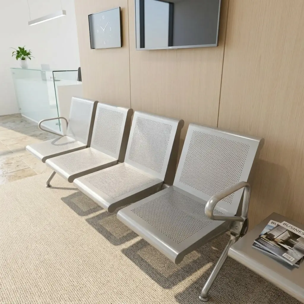 Heavy-duty 4-seater silver steel waiting room bench with perforated metal backrests, integrated armrests, and chrome legs on a textured rug in a public reception area.