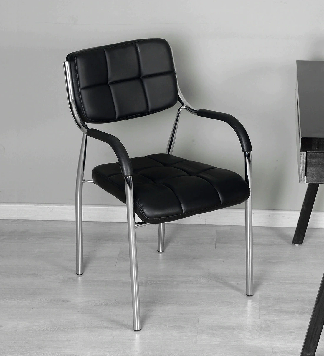 Stackable black leather visitor chair with chrome metal frame and padded armrests for office waiting areas.