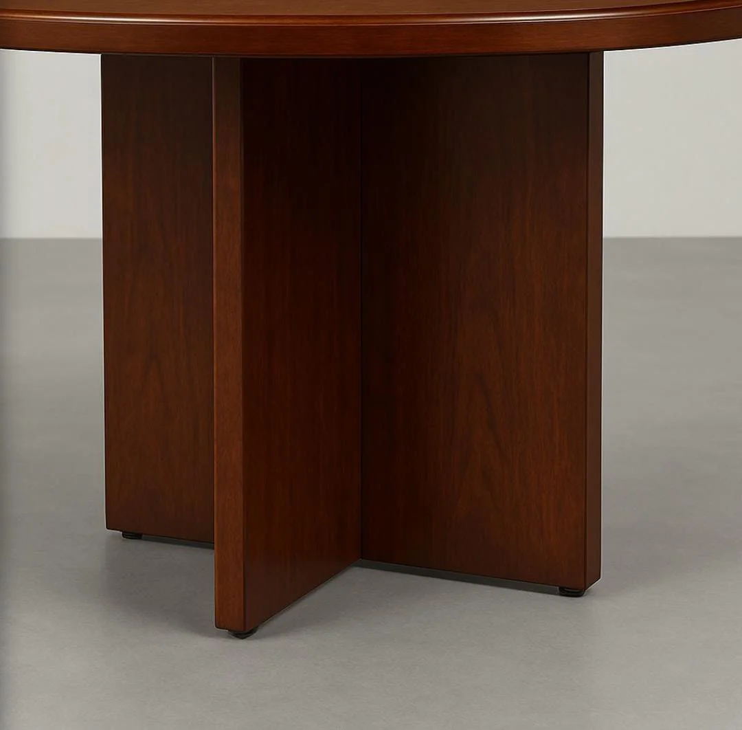 Round conference table in a rich cherry wood veneer finish, featuring a thick, circular tabletop with a classic bevelled edge detail, supported by a central, intersecting X-shaped wooden pedestal base.