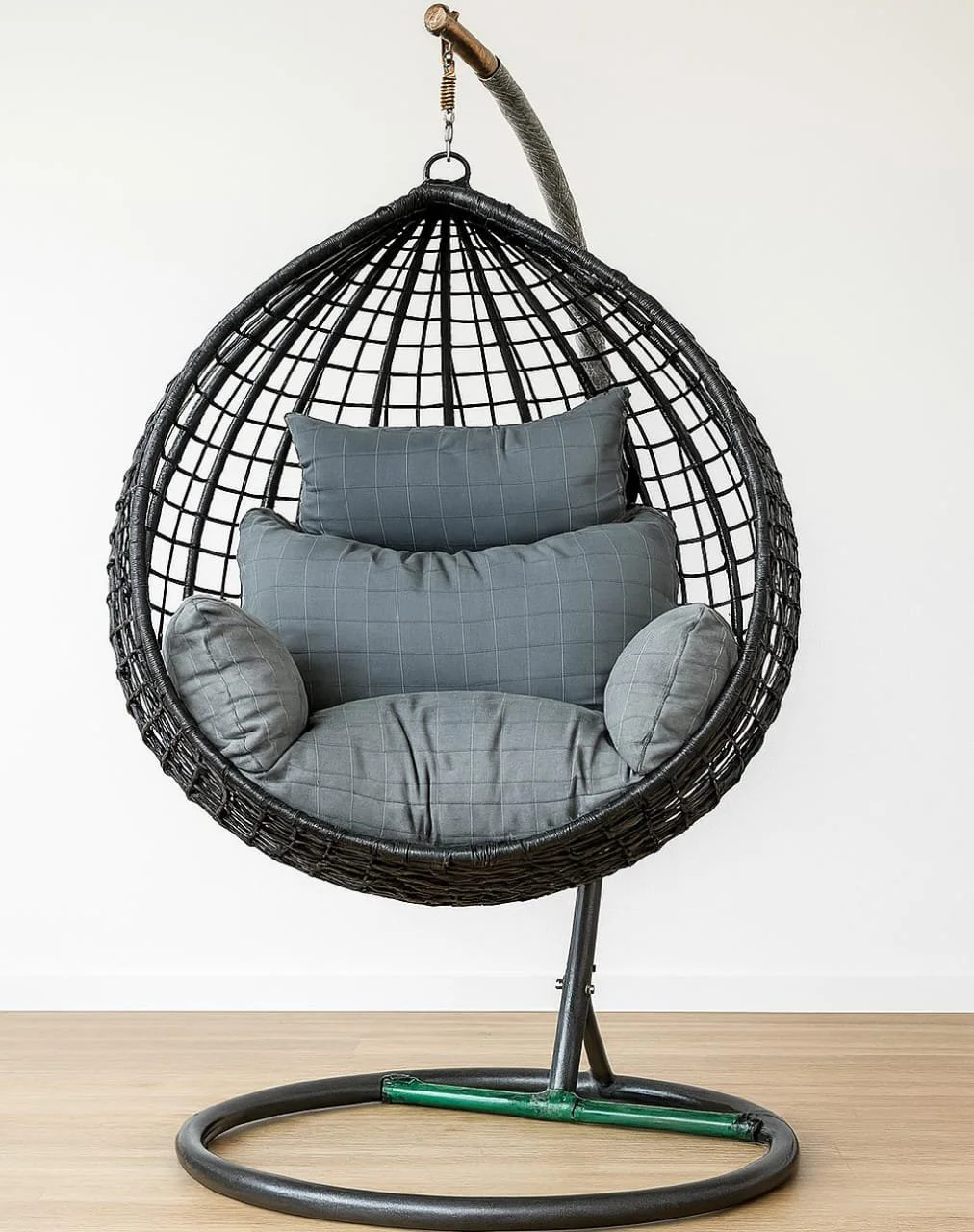 Premium black woven rattan egg chair swing featuring a teardrop open-grid basket design, a plush gray tufted seat cushion with an integrated headrest pillow, suspended from a heavy-duty black steel C-stand.