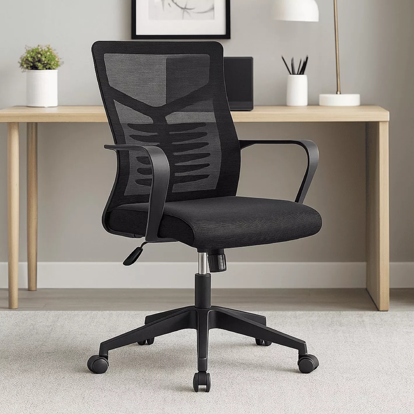 Swivel Ergonomic Office Task Chair featuring a mid-back black mesh backrest with a visible skeletonized lumbar support structure, fixed black polymer loop armrests, a contoured black fabric padded seat cushion, an under-seat pneumatic height adjustment lever, and a five-star black nylon swivel base on dual-wheel casters.