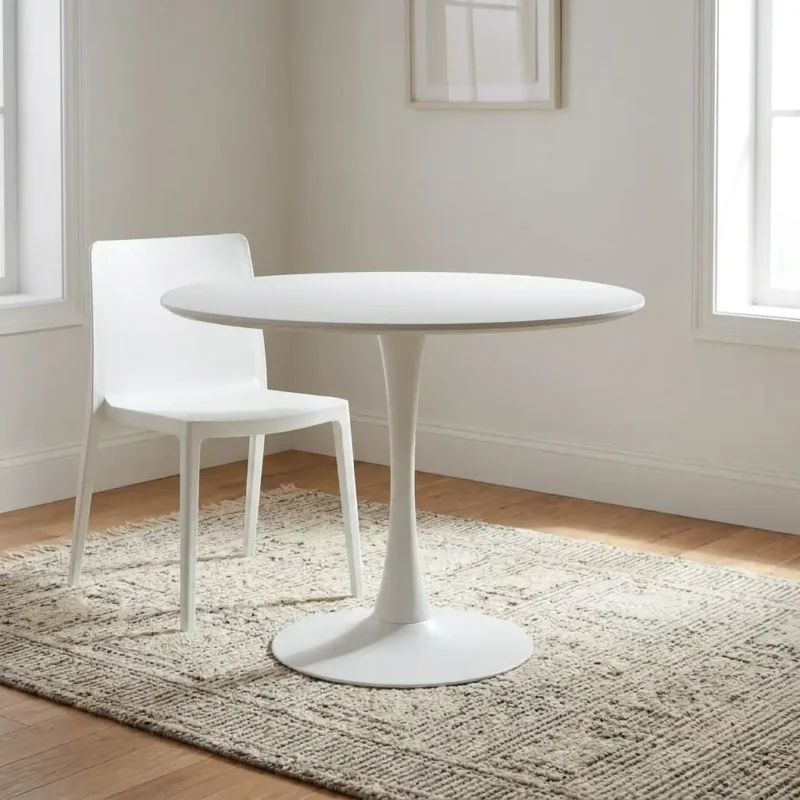 Circular white dining table in a matte white finish, featuring a round minimalist tabletop supported by a sleek, central trumpet-shaped pedestal tulip base.