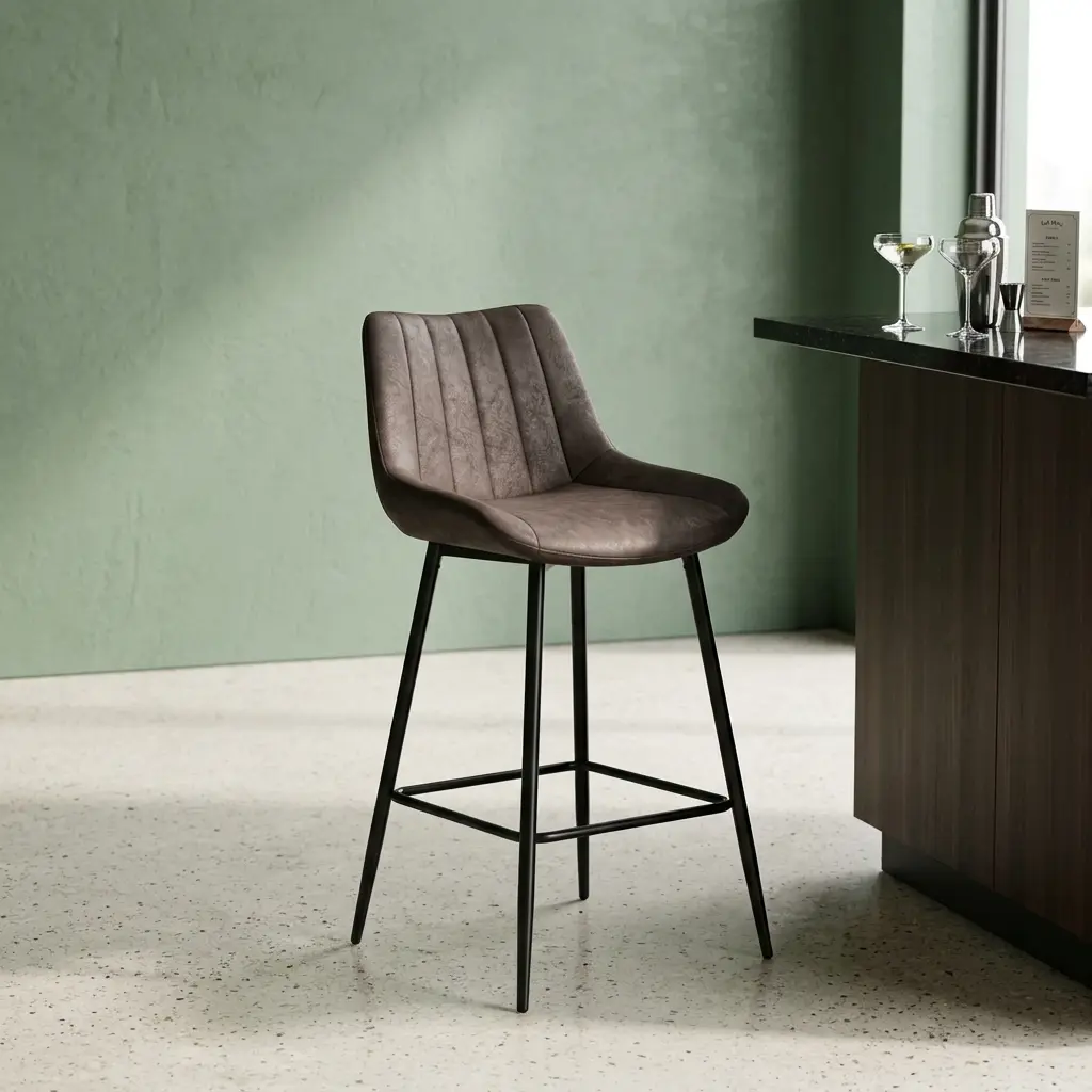 Gray modern leather barstool featuring a contoured bucket seat upholstered in dark charcoal gray faux leather with vertical channel stitching details, supported by a sleek, matte black four-legged metal frame with a built-in square footrest ring.