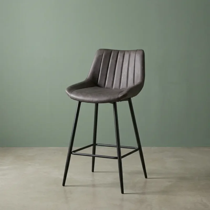 Gray modern leather barstool featuring a contoured bucket seat upholstered in dark charcoal gray faux leather with vertical channel stitching details, supported by a sleek, matte black four-legged metal frame with a built-in square footrest ring.
