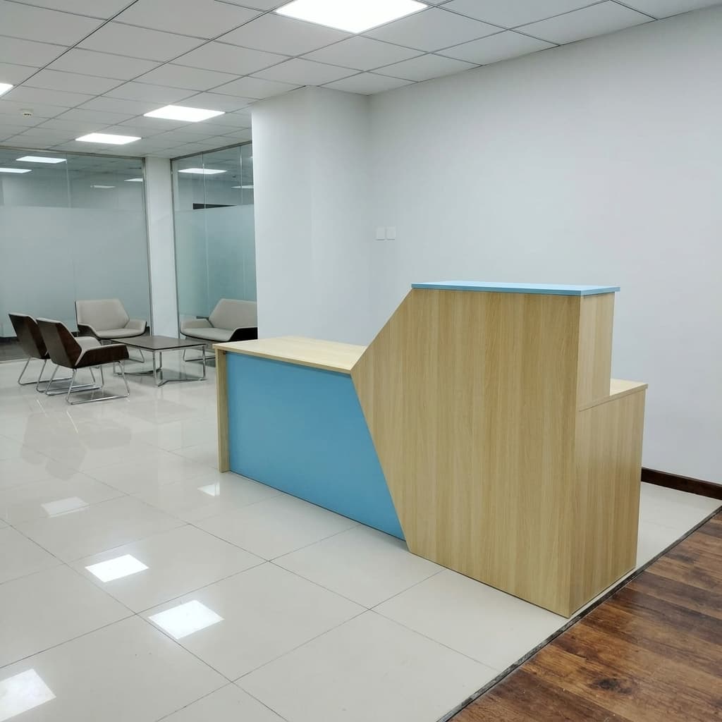 180cm modern reception table showcasing a contemporary dual-level geometric design, featuring a low light oak wood transaction counter with a smooth sky blue front panel that cuts diagonally into a raised light oak privacy riser topped with a matching sky blue counter shelf.
