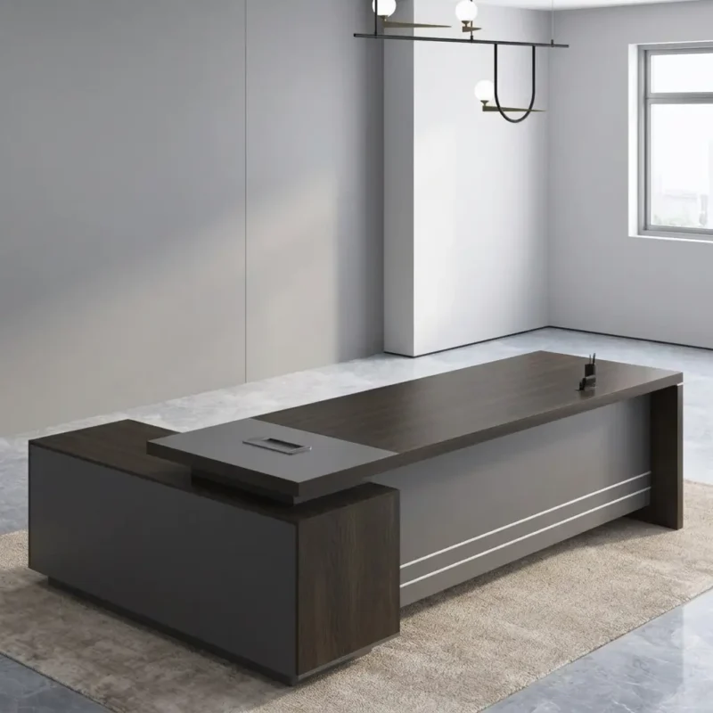 1.6m L-shaped executive desk featuring a dark walnut wood-grain main desktop, an integrated charcoal grey side return cabinet with a raised cable management hub, a full front modesty panel with dual horizontal metallic accent stripes, and sturdy panel leg supports.