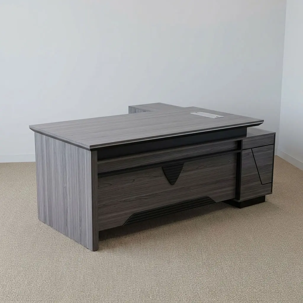 L-shaped 1800mm office table featuring a dark grey wood-grain laminate finish, dual desktop flip-top cable management ports, a front modesty panel with geometric black accent detailing, an integrated side return extension unit providing additional work surface and storage, and solid panel-style engineered wood base supports.