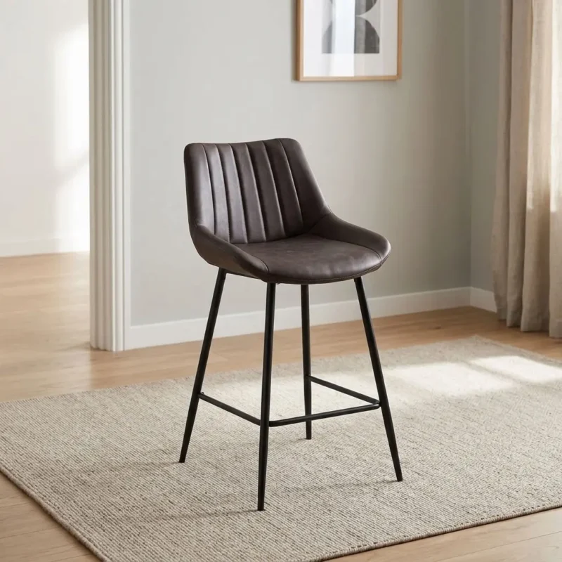 Modern gray kitchen barstool featuring distressed dark gray leatherette upholstery with vertical channel tufting on the low backrest, a scoop seat design, an armless profile, integrated lower footrest stretchers, and slender black powder-coated metal legs.