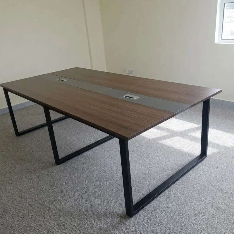 2.4metres boardroom table featuring a walnut wood-grain laminate desktop, a central grey cable management raceway inlay with integrated pop-up power/data access covers, and heavy-duty black powder-coated steel O-frame loop legs.