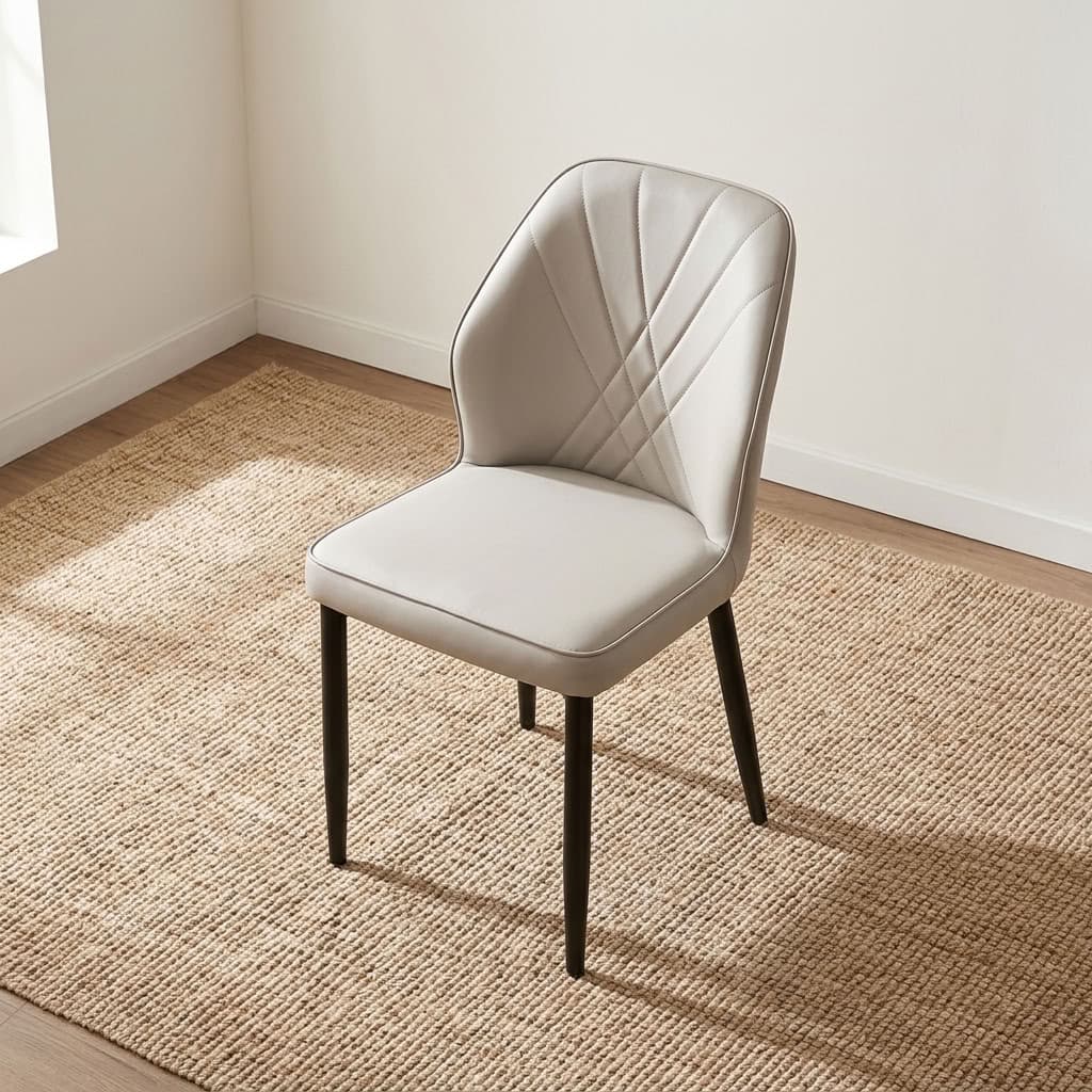 Modern leather dining chair featuring light gray faux leather upholstery with fan-style accent stitching on the inner backrest, a padded bucket-style seat with subtle side curves, an armless profile, and slim tapered black powder-coated metal legs.