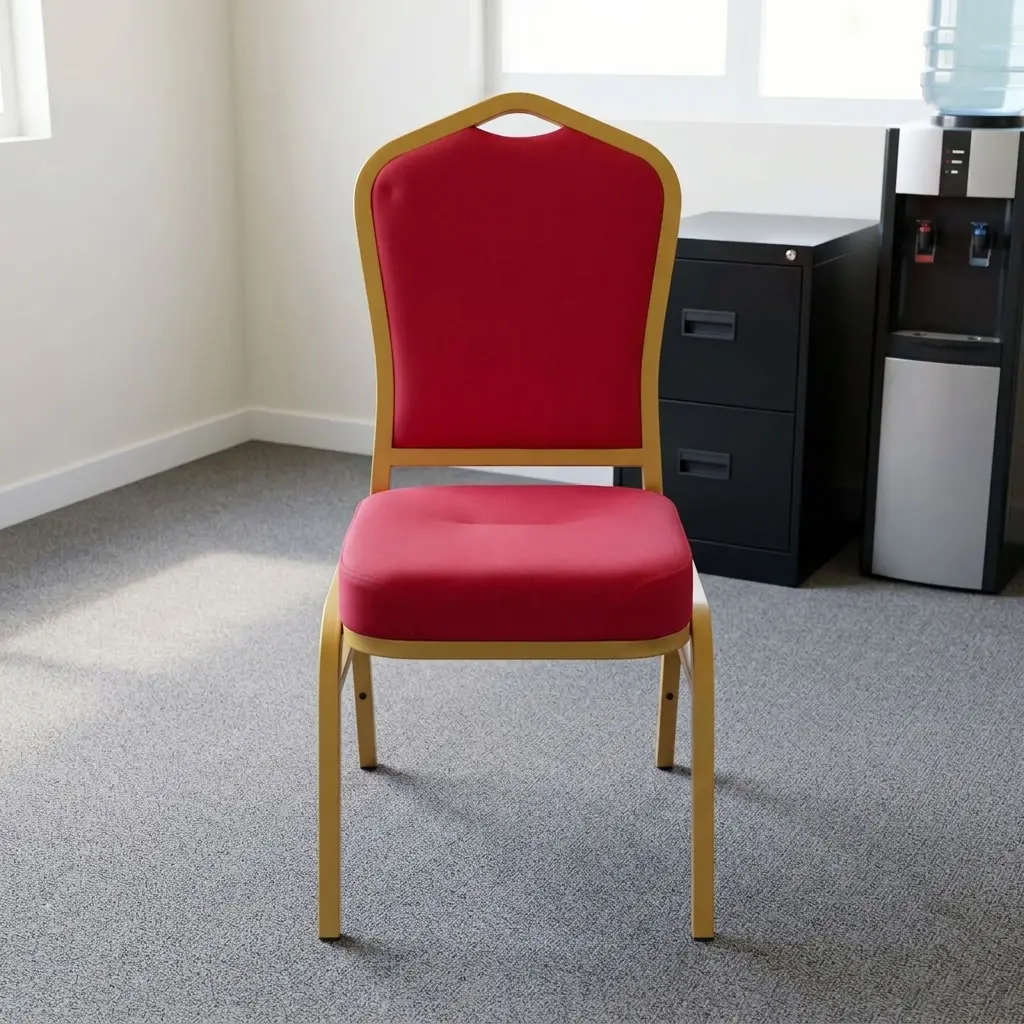 Heavy duty red conference chair featuring a crown-back profile with red fabric upholstered backrest and a high-density padded seat cushion, a stackable armless frame design with protective stacking bumpers, and a gold powder-coated square steel tube four-leg base with non-marring floor glides.